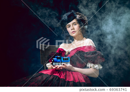 Young woman as Anna Karenina on dark blue background. Retro style, comparison of eras concept. Young woman as Anna Karenina on dark blue background. Retro style, comparison of eras concept. 69363741
