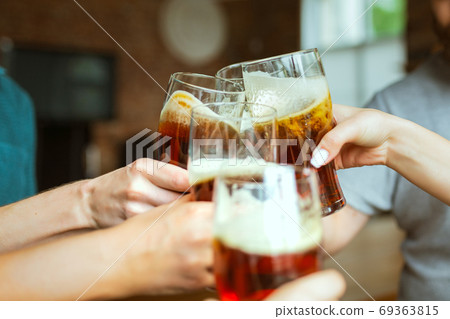 Young group of friends drinking beer, having fun, laughting and celebrating together. Close up clinking beer glasses Young group of friends drinking beer, having fun, laughting and celebrating together. Close up clinking beer glasses 69363815