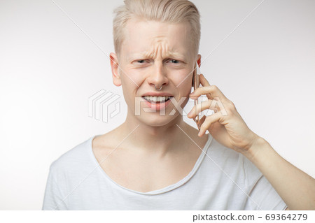 Annoyed male with frowned face recieving unpleasant news on mobile phone. Annoyed male with frowned face recieving unpleasant news on mobile phone. 69364279