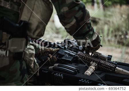 The soldier pulls a rifle out of the ammunition case and insert ammunition clip into assault rifle 69364752