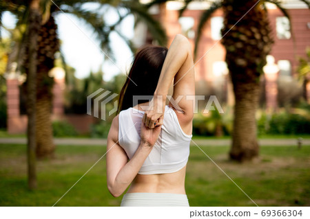Young woman doing Yoga outdoors in park in white sportswear. Active vacation. 69366304