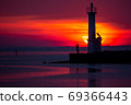 sun rising behind lighthouse along with fisherman 69366443
