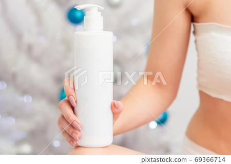 Cosmetics white bottle in hand of young female Cosmetics white bottle in hand of young female 69366714