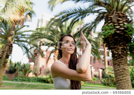 Young woman doing Yoga outdoors in park in white sportswear. Active vacation. 69366808