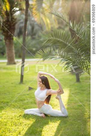 Young attractive woman practicing yoga outdoor over nature background. 69366809