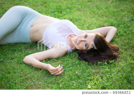 Joyful woman lying on green grass on park medow. Outdoors. Enjoy Nature. 69366851