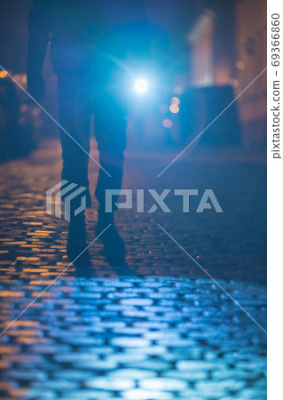 The man with a flashlight stand on the road. Evening night time 69366860