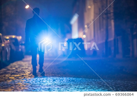 The man with a flashlight stand on the road. Evening night time 69366864