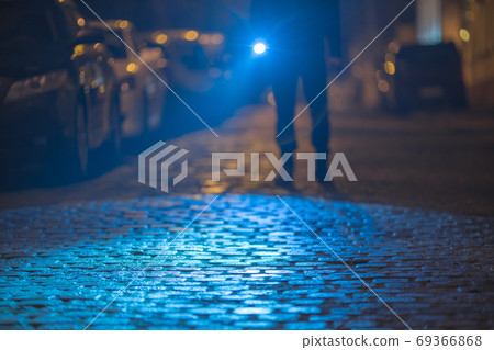 The man with a flashlight inspect the street. Evening night time The man with a flashlight inspect the street. Evening night time 69366868