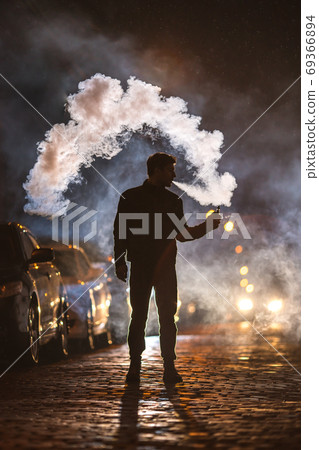 The man smoke electronic cigarette in the street. Evening night time 69366894