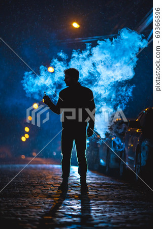 The man stand near the cloud of smoke. Evening night time 69366896