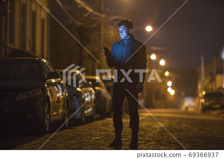 The man phone on the street. Evening night time. Telephoto lens shot The man phone on the street. Evening night time. Telephoto lens shot 69366937