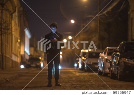 The man phone on the street. Evening night time. Telephoto lens shot 69366947