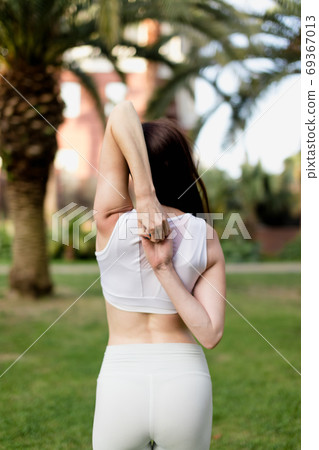 Young woman doing Yoga outdoors in park in white sportswear. Active vacation. 69367013