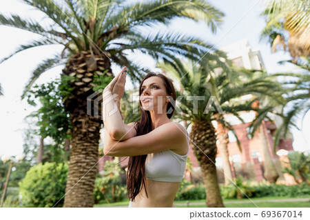 Young woman doing Yoga outdoors in park in white sportswear. Active vacation. 69367014