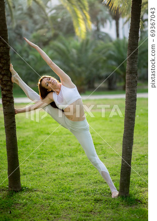 Attractive woman practicing fitness working out outdoors over nature background 69367043