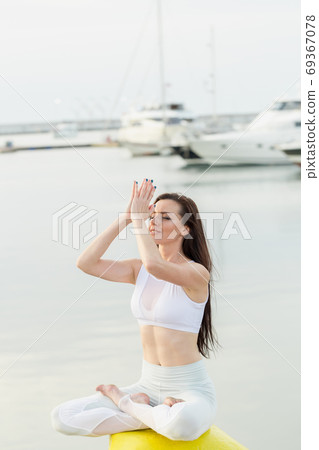 Sportsgirl in active clothes relaxing on sea pier after outdoor workout Sportsgirl in active clothes relaxing on sea pier after outdoor workout 69367078