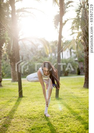 Attractive woman doing yoga tree pose, balancing on one leg, with raised hands. Attractive woman doing yoga tree pose, balancing on one leg, with raised hands. 69367129