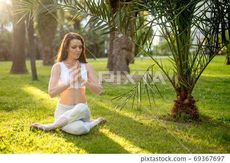 Fitness woman training yoga in cow head pose in nature background. 69367697