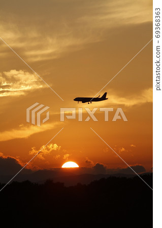 Airplane flying against the setting sun Airplane flying against the setting sun 69368363