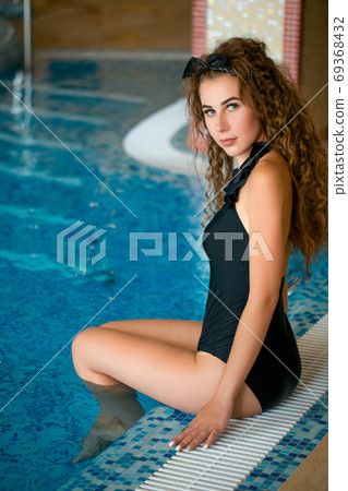 Young woman relaxing in swimming pool, enjoying cool water in a hot sunny day Young woman relaxing in swimming pool, enjoying cool water in a hot sunny day 69368432