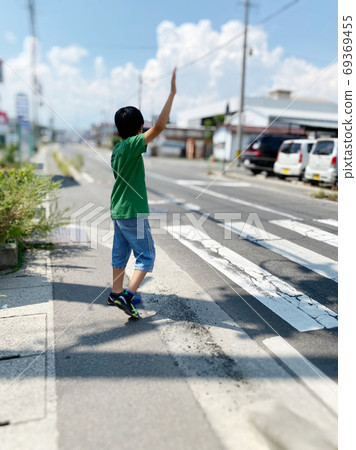 Elementary school students raising their hands and crossing the pedestrian crossing Elementary school students raising their hands and crossing the pedestrian crossing 69369455