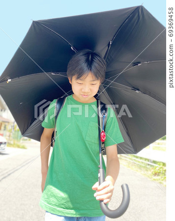 小學生在炎熱的天氣中帶著太陽傘散步 69369458