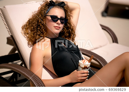 The sunbathing woman near a swimming pool The sunbathing woman near a swimming pool 69369829