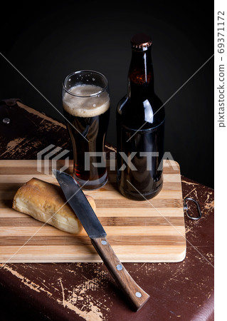 Glass and Bottle of dark beer with smoked cheese on cutting boar Glass and Bottle of dark beer with smoked cheese on cutting boar 69371172