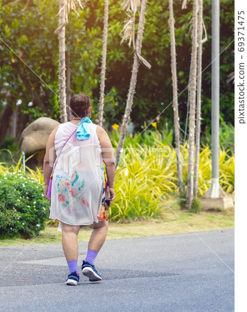 Back view of a Asian elderly woman wears earphone to listening song walking and jogging for good health in public park.Senior jogger in nature. Older female enjoying Peaceful nature.Healthcare concept Back view of a Asian elderly woman wears earphone to listening song walking and jogging for good health in public park.Senior jogger in nature. Older female enjoying Peaceful nature.Healthcare concept 69371475