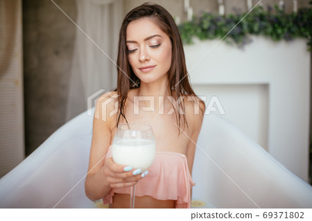 Sensual attractive woman relaxing in bath with glass of milk. Sensual attractive woman relaxing in bath with glass of milk. 69371802