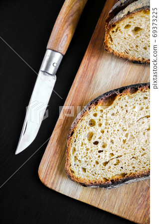 Traditional French country bread slices and pocket knife on a cu Traditional French country bread slices and pocket knife on a cu 69373225