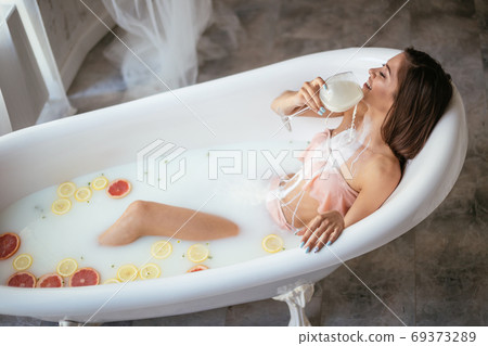 Sensual attractive woman relaxing in bath with glass of milk. Sensual attractive woman relaxing in bath with glass of milk. 69373289