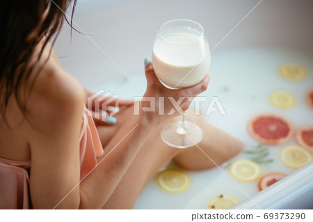 Sensual attractive woman relaxing in bath with glass of milk. Sensual attractive woman relaxing in bath with glass of milk. 69373290
