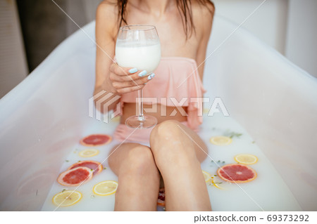 Sensual attractive woman relaxing in bath with glass of milk. Sensual attractive woman relaxing in bath with glass of milk. 69373292