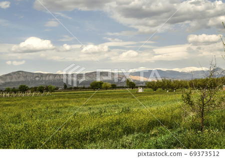 Valley with apricot orchards, vineyards on the background of the spring evening sky and the mountains of Geghama ridge in Armenia Valley with apricot orchards, vineyards on the background of the spring evening sky and the mountains of Geghama ridge in Armenia 69373512