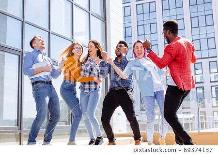 Group of multi ethnic youngsters chilling in urban outdoor background Group of multi ethnic youngsters chilling in urban outdoor background 69374137