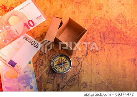 Compass beside a box and Euro banknotes  on an old map 69374478