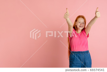 Caucasian teen girl's portrait isolated on coral pink studio background. 69374541