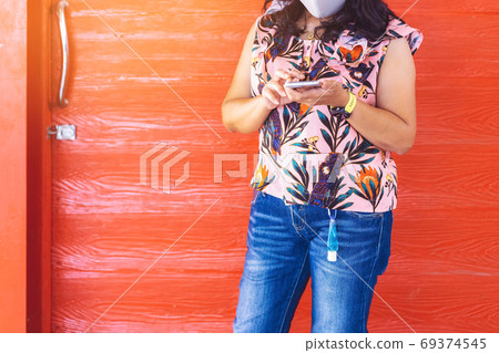 Mini portable alcohol gel bottle to kill Corona Virus(Covid-19) hanging on belt loop of woman' s jeans with plank background. New normal lifestyle. Health care concept. Selective focus on alcohol gel 69374545