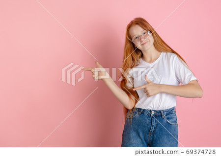 Caucasian teen girl's portrait isolated on coral pink studio background. Caucasian teen girl's portrait isolated on coral pink studio background. 69374728