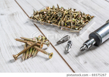 Group of Screw bolts with screwdriver on wooden background. Group of Screw bolts with screwdriver on wooden background. 69375267