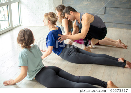 Group of caucasian women practicing yoga under instructors guidance in studio Group of caucasian women practicing yoga under instructors guidance in studio 69375817