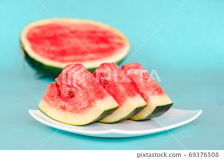 Water melon slices on a plate on blue background Water melon slices on a plate on blue background 69376508