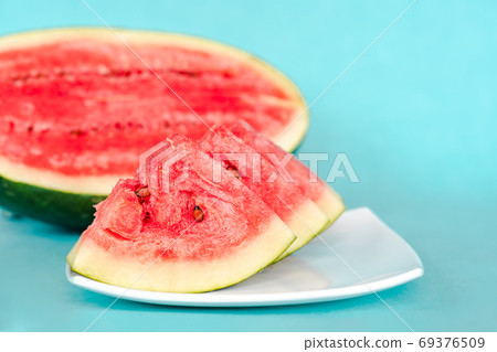 Water melon slices on a plate on blue background Water melon slices on a plate on blue background 69376509