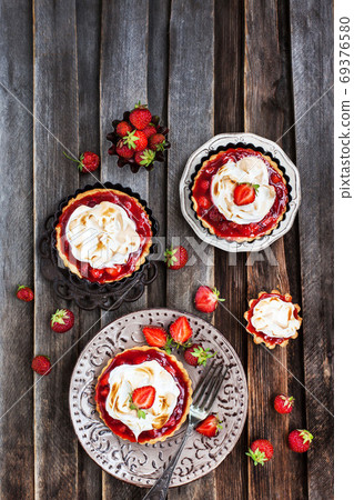Strawberry meringue tartlets on wooden rustic background 69376580