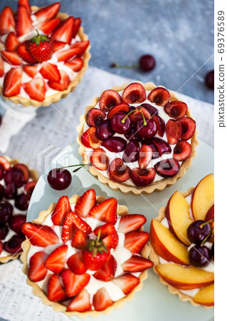 Fresh delicious cherry, strawberry and peach tartlets on gray ba Fresh delicious cherry, strawberry and peach tartlets on gray ba 69376589