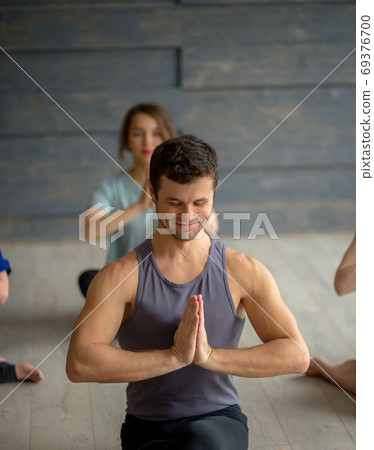 Handsome young muscular man, yogi teacher conducting yoga to caucasian women. Handsome young muscular man, yogi teacher conducting yoga to caucasian women. 69376700