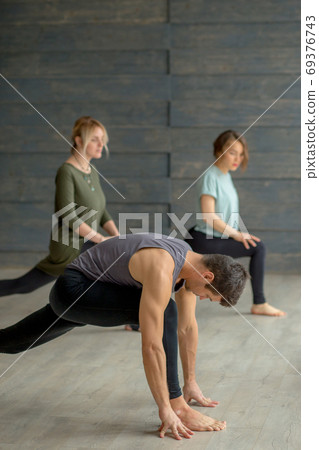 Yoga beginners exercising against grey wall, doing yoga or pilates posture. 69376743