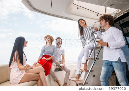 Travel, seatrip, friendship and people concept - friends sitting on yacht deck Travel, seatrip, friendship and people concept - friends sitting on yacht deck 69377020